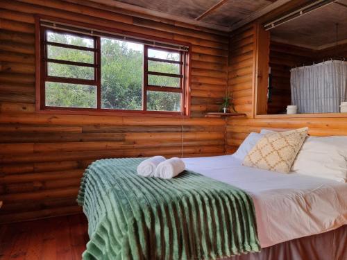 a bed in a log cabin with two towels on it at Mansfield Private Reserve in Port Alfred