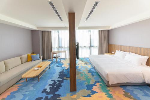 JANDA Golden Tulip Hotel في Wuqi: غرفه فندقيه بسرير واريكه