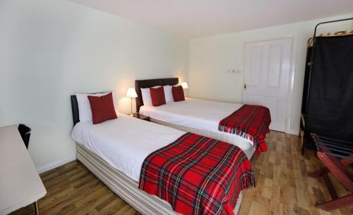 two beds in a hotel room with red pillows at Hillhead Farm Lets in Stirling