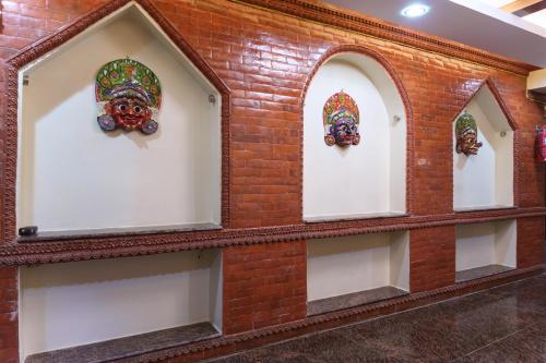 a brick wall with three windows with masks on it at Sweet Inn in Bhaktapur
