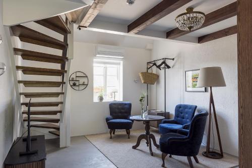 a living room with blue chairs and a spiral staircase at Ekenäs Gård på Österlen in Kivik