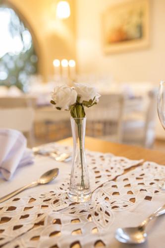 a glass vase with white roses in it on a table at Astron Hotel Bauru by Nobile in Bauru