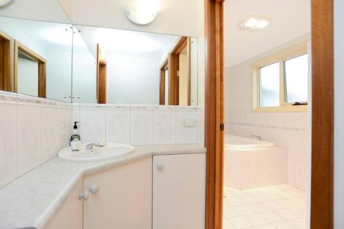 a white bathroom with a sink and a mirror at Esplanade Escape Absolute Beachfront WIFI-NBN in Middleton