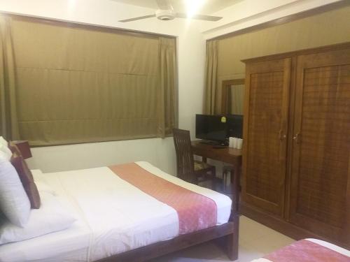 a bedroom with a bed and a desk with a computer at De Mansion Hotels in Katugastota