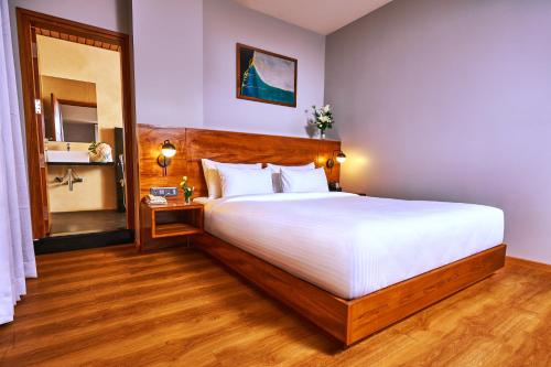 a bedroom with a large white bed and a mirror at Visthara Hotel in Bangalore