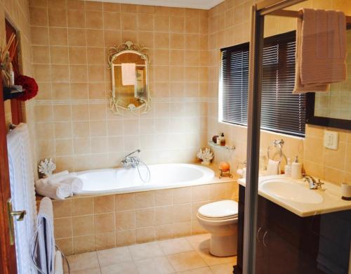 a bathroom with a tub and a toilet and a sink at Serendipity Cottage in Johannesburg