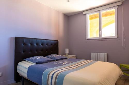 Schlafzimmer mit einem Bett mit einem schwarzen Kopfteil und einem Fenster in der Unterkunft Guest house calme proche mer in Bourgneuf-en-Retz