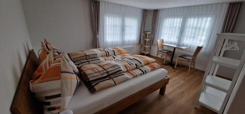 um quarto com uma cama, uma mesa e janelas em Gasthaus Hirschen AG, Oberiberg em Oberiberg