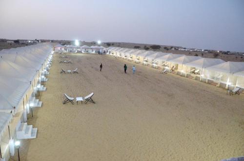 a beach with white tents and people walking on it at Marina Dessert Camp in Sām