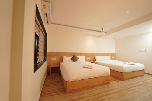a bedroom with two beds and a tv on the wall at Southern Residency in Cochin
