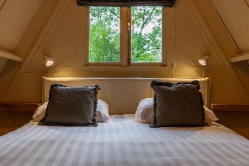 ein Bett mit zwei Kissen in einem Zimmer mit einem Fenster in der Unterkunft La Petite Ourse Durbuy - natuur chalet in het bos in Durbuy