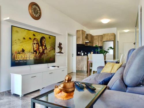 sala de estar con sofá azul y TV de pantalla plana en Oyster Flats - Seaside Apartment 7 en Żebbuġ