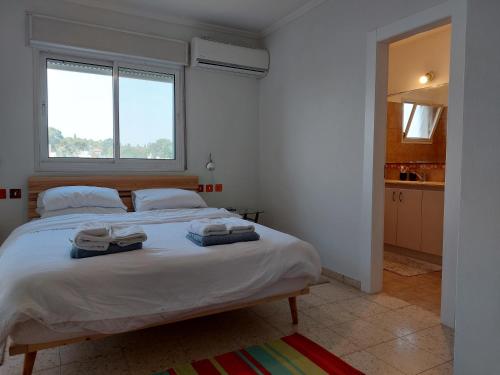 a bedroom with a large bed with towels on it at Happy Vacation House in Zikhron Ya‘aqov