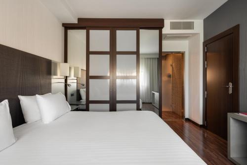 a bedroom with a large bed with white sheets at Exe Zizur Pamplona in Zizur Mayor