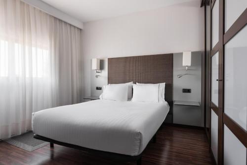 a bedroom with a large white bed with white pillows at Exe Zizur Pamplona in Zizur Mayor