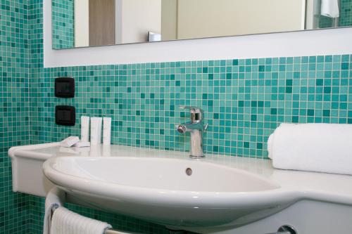 un bagno con lavandino, specchio e piastrelle verdi di Residence al Palace a Vasto
