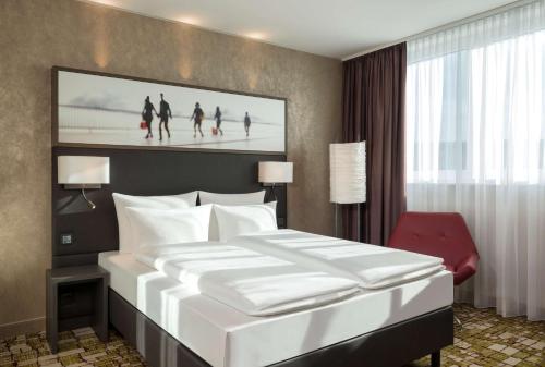 a bedroom with a large white bed and a red chair at Dorint Airport-Hotel Zürich in Glattbrugg