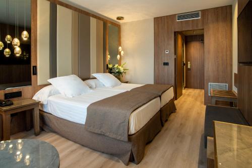 a hotel room with a large bed and a table at Hotel Granada Center in Granada