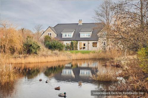 a house on a lake with ducks in the water at Vakantiepark De Krim Texel in De Cocksdorp