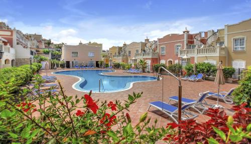 a swimming pool in a yard with chairs and buildings at Luxury House Paraiso Del Palm Mar in Palm-mar