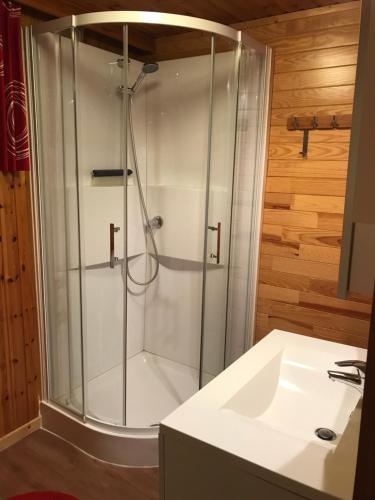a shower with a glass door next to a sink at Aux Bons Vivants in Heure
