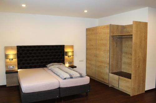 a bedroom with a large bed and a wooden cabinet at Waldhotel Rainau in Ellwangen