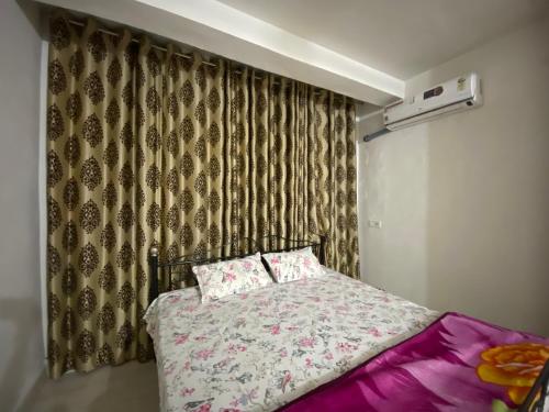 a bedroom with a bed with pink sheets and a curtain at Blue King in Jaipur