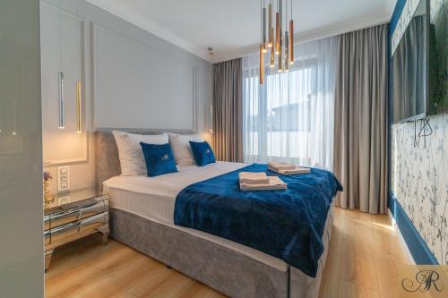 a bedroom with a large bed with blue pillows at Apartament Rosa De Lux in Mińsk Mazowiecki