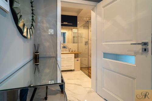 bagno con porta bianca e doccia di Apartament Rosa De Lux a Mińsk Mazowiecki
