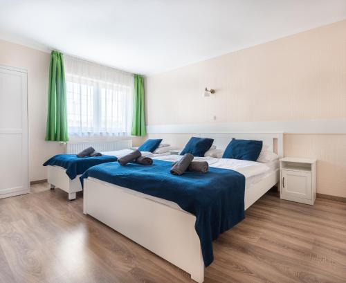 two beds in a bedroom with green curtains at Bagolyvár Inárcs in Inárcs