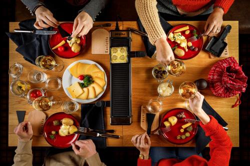a group of people sitting around a table with food at Hotel Sport Klosters in Klosters