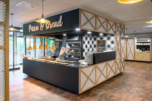 a bakery counter with a woman preparing food at Terme Olimia - Hotel Breza in Podčetrtek