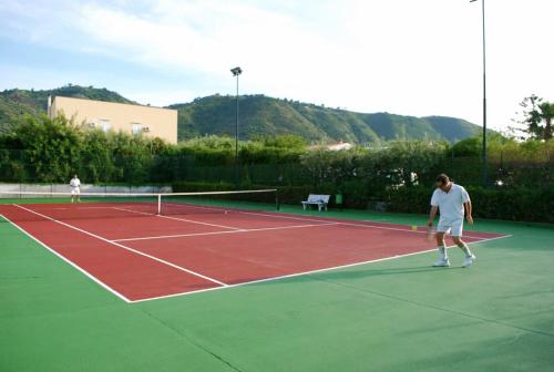 two people playing tennis on a tennis court at Hotel Baia Del Capitano in Cefalù