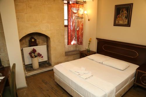 a bedroom with a bed in a room with a fireplace at KALE EVİ BUTİK OTEL in Şahinbey