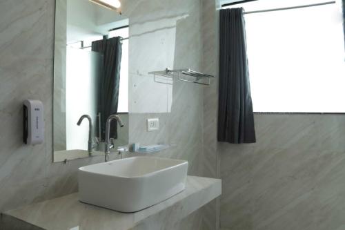La salle de bains est pourvue d'un lavabo blanc et d'un miroir. dans l'établissement Sandbanks Beach Resort, à Arambol