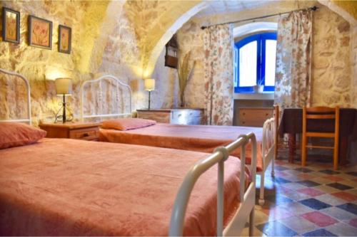 a bedroom with two beds and a window at Ta'Martin Farmhouse Xewkija Gozo in Xewkija
