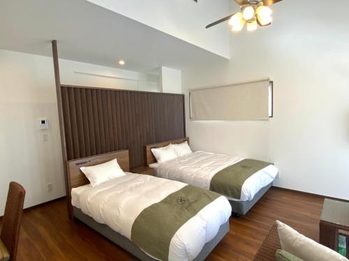 a hotel room with two beds and a ceiling fan at VILLA COZYSTAY92 宮古島 in Miyako Island