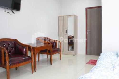 a dining room with a table and chairs and a bed at Brahma Hotel Mitra RedDoorz in Jakarta