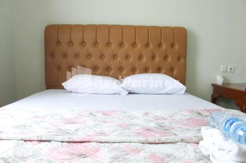 a bed with a large headboard and two pillows at Brahma Hotel Mitra RedDoorz in Jakarta