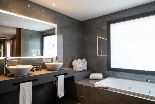 a bathroom with two sinks and a tub and a large mirror at Hotel Granada Center in Granada