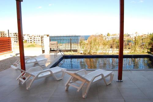 a patio with three chairs and a swimming pool at Coral Luxury Villas in Lozenets