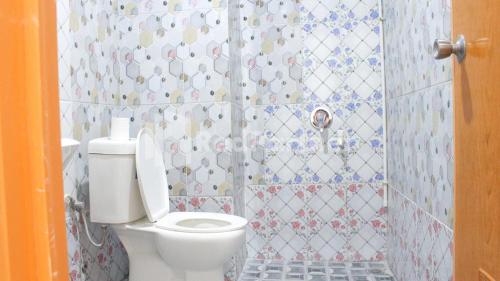 a bathroom with a toilet and a tiled shower at Brahma Hotel Mitra RedDoorz in Jakarta