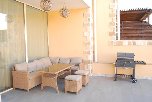 a patio with a couch and a table and a grill at Coral Luxury Villas in Lozenets