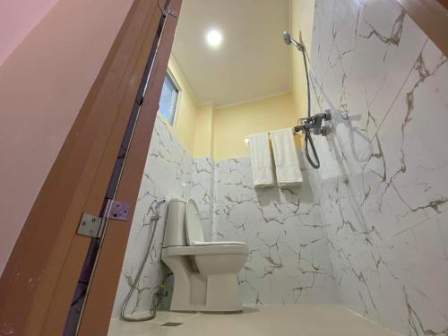 a bathroom with a toilet and a marble wall at Divine Resort Corporation in Moalboal