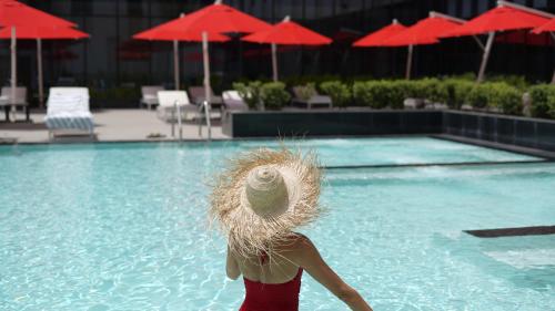 a woman wearing a straw hat standing in front of a swimming pool at Maani Muscat Hotel & Suites in Muscat
