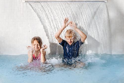 two children playing in the water in a swimming pool at Maani Muscat Hotel & Suites in Muscat