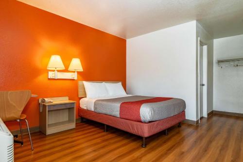 a small bed in a room with an orange wall at Motel 6-Palm Springs, CA - East - Palm Canyon in Palm Springs
