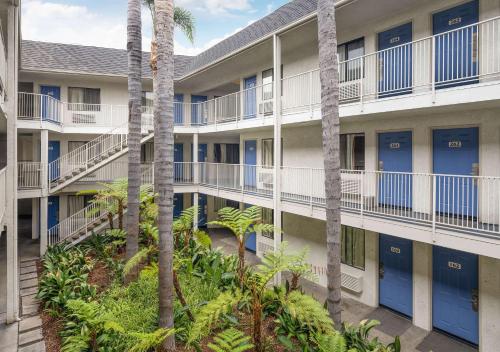 an apartment building with blue doors and palm trees at Motel 6-Buena Park, CA - Knotts Berry Farm - Disneyland in Buena Park