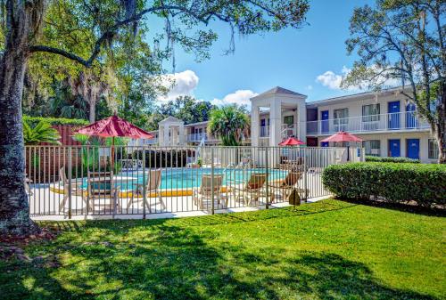 a fence with chairs and umbrellas next to a pool at Motel 6-Tallahassee, FL - Downtown in Tallahassee