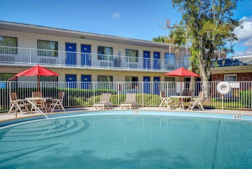 uma piscina com cadeiras e guarda-sóis em frente a um hotel em Motel 6-Tallahassee, FL - Downtown em Tallahassee